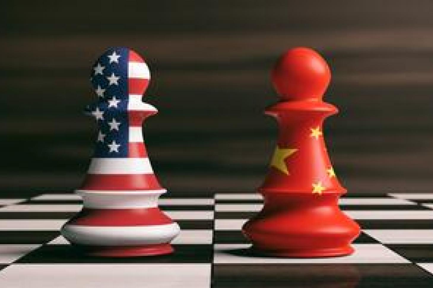 Two chess pieces, one with an American flag and one with a Chinese flag