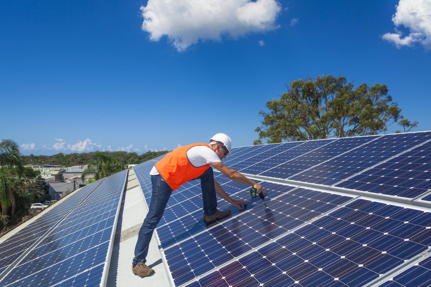 A technician installing solar panels on a roof.