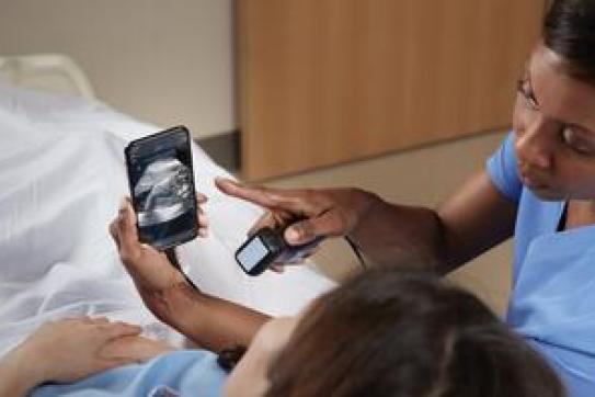 A healthcare working showing a woman a sonogram image on a cellphone.