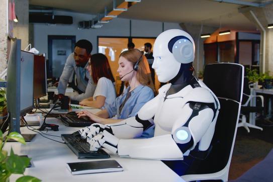 A robot working at a desk with human workers