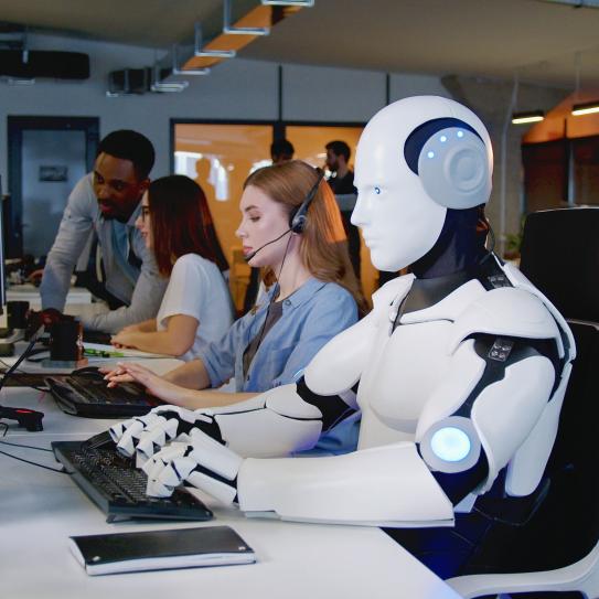 A robot working at a desk with human workers